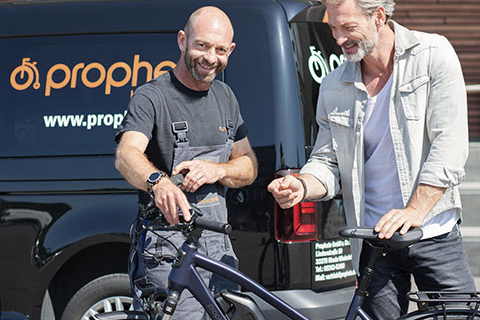 Prophete Techniker mit Kunden beim Service des Fahrrads